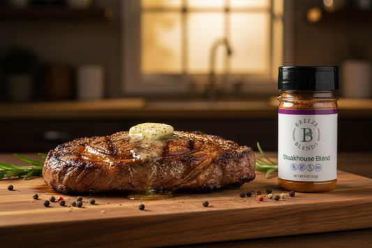 Perfectly grilled ribeye steak with a golden crust resting on a wooden cutting board with butter melting on top, with Breeze Blends all-natural Steakhouse Blend beside it