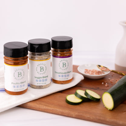 Breeze Blends BBQ pack of three spice jars labeled 'Poultry Blend', 'Veggie Blend', and 'Steakhouse Blend' on a cutting board with zucchini slices.