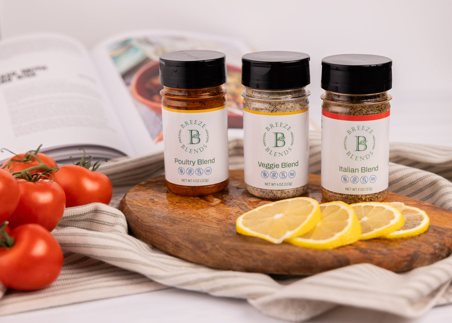 Breeze Blends Tuscan Pack of three spice jars labeled 'Poultry Blend', 'Veggie Blend', and 'Italian Blend' on a wooden board with lemons and tomatoes.