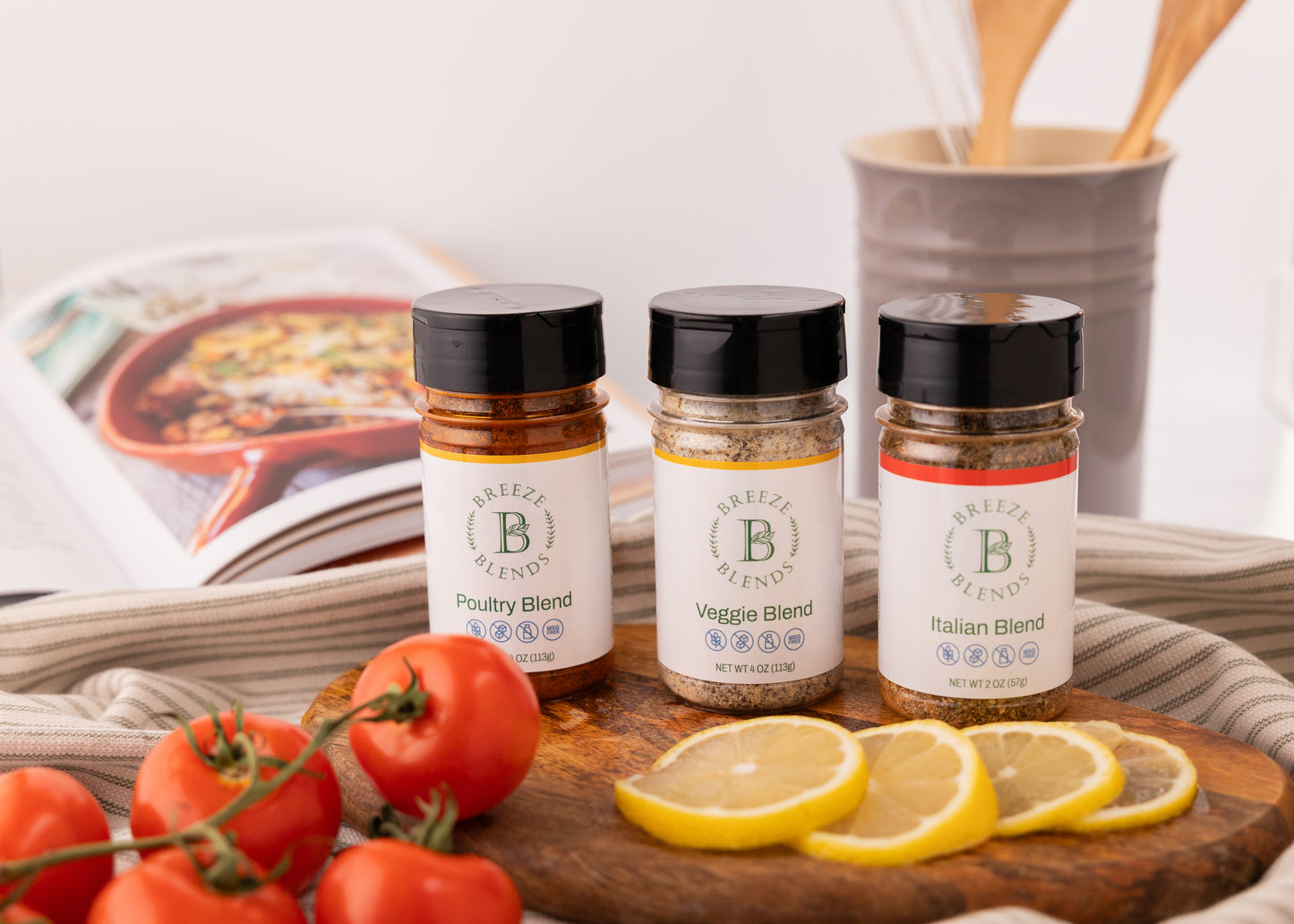 Breeze Blends bottles included in Tuscan Pack. On a wooden board with tomatoes and lemons, next to an open cookbook.