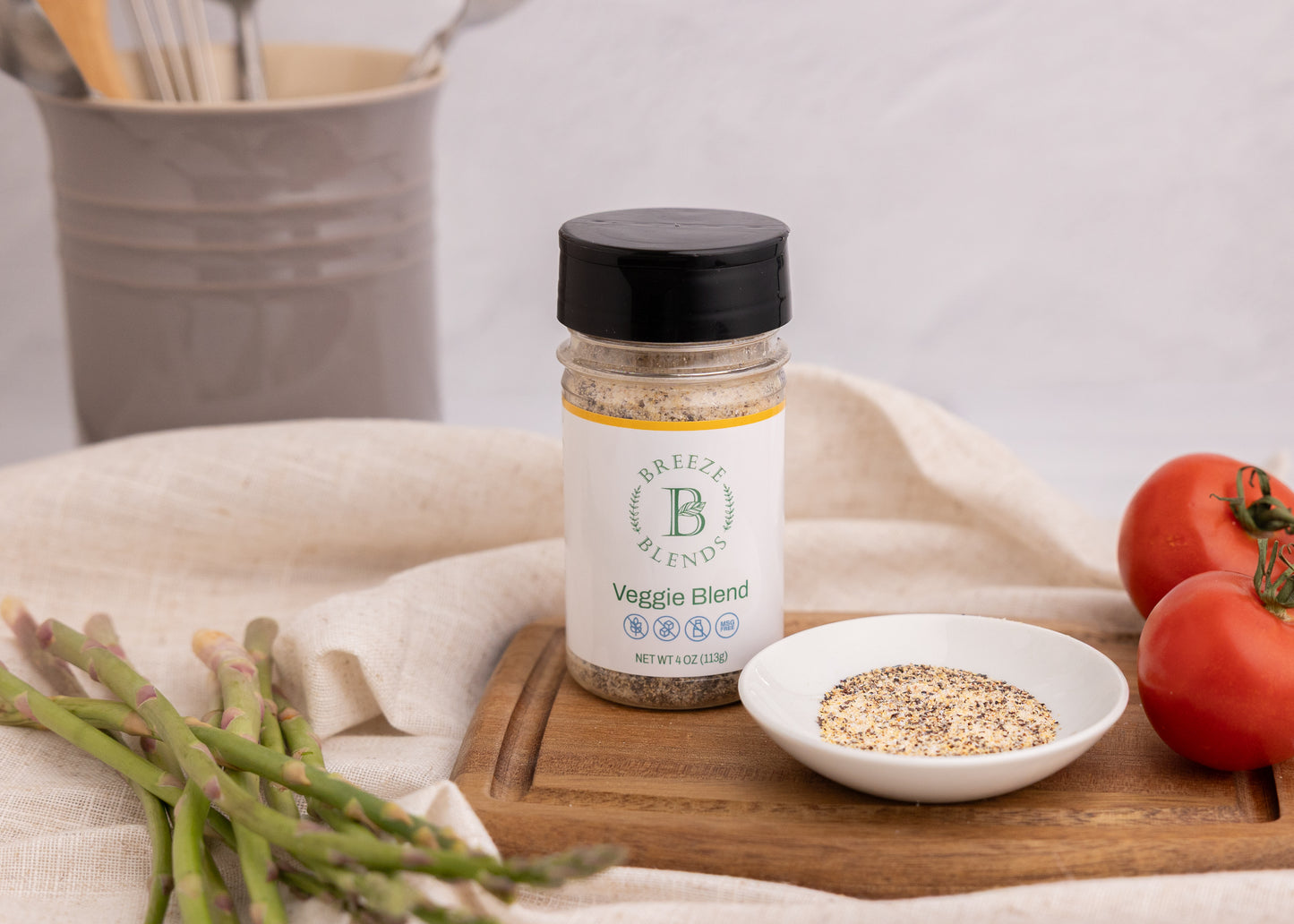 Bottle of Breeze Blends Veggie Blend on a wooden cutting board with tomatoes and asparagus.