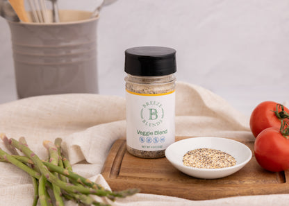 Bottle of Breeze Blends Veggie Blend on a wooden cutting board with tomatoes and asparagus.