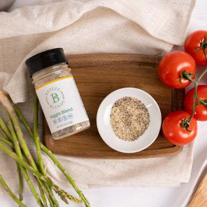 Breeze Blends Veggie blend jar on a wooden board with a bowl of blended ingredients, tomatoes, and asparagus.