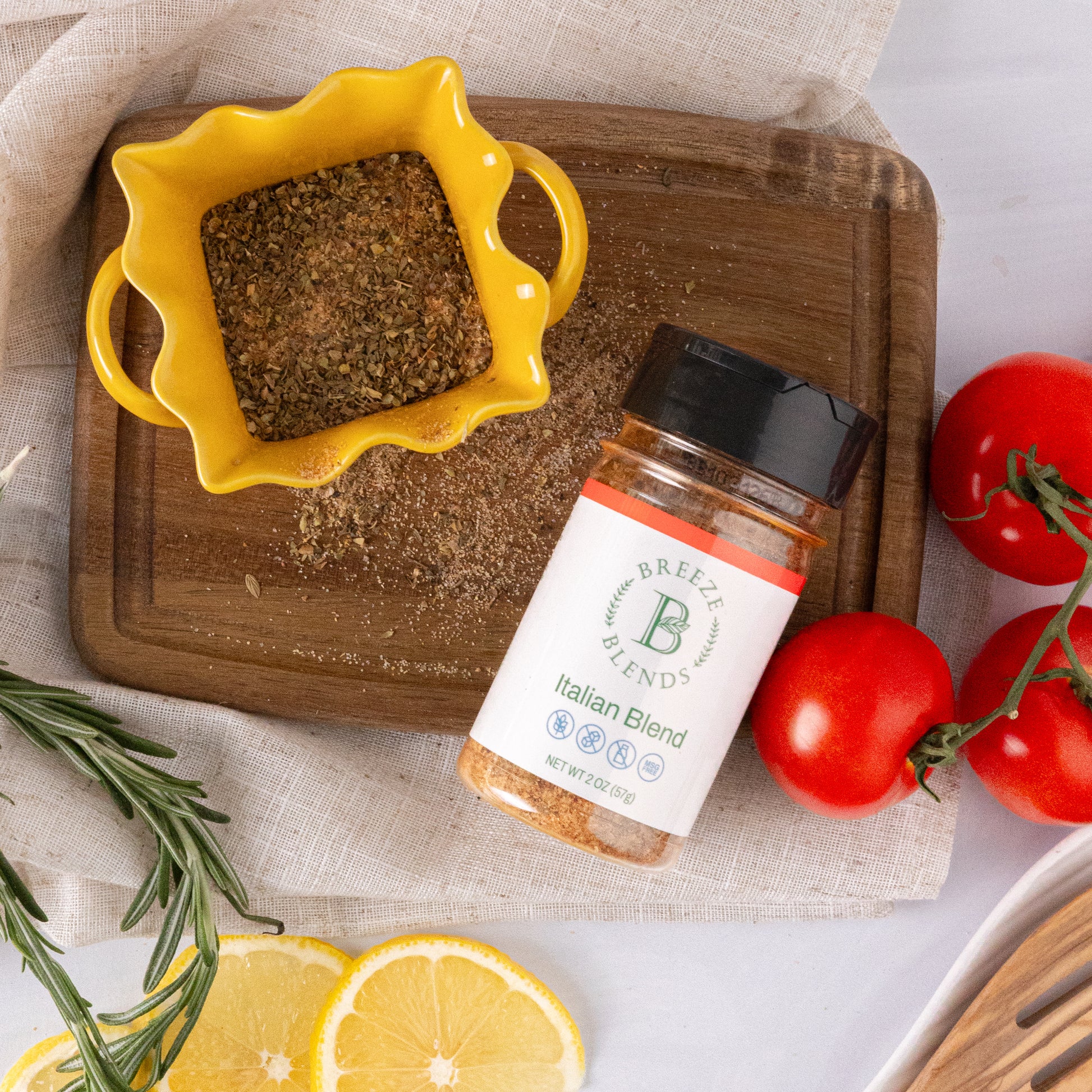 Bottle of Breeze Blends Italian Blend on a wooden cutting board with tomatoes and lemon slices.