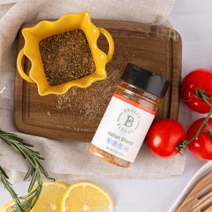 Bottle of Breeze Blends Italian Blend on a wooden cutting board with tomatoes and lemon slices.