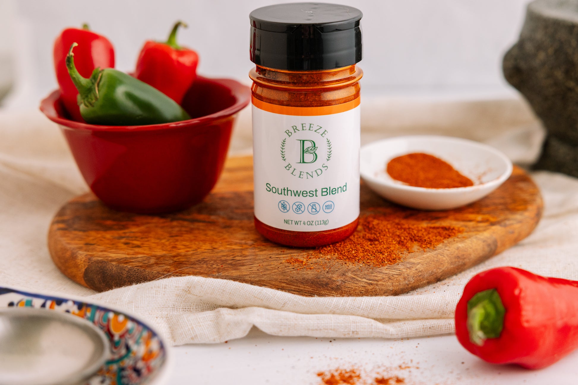 Breeze Blends Southwest Blend spice jar on a wooden cutting board with peppers and spices in the background.