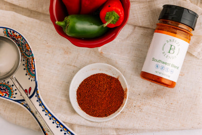 Bottle of Breeze Blends Southwest Blend in a small bowl with a bottle of seasoning and peppers on a textured surface