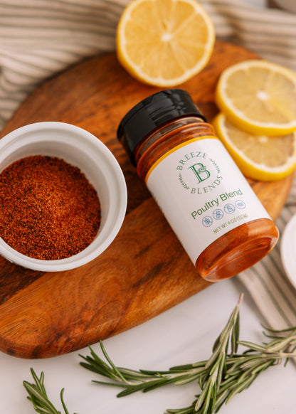Bottle of Breeze Blends Poultry Blend on a wooden cutting board with lemons and spices