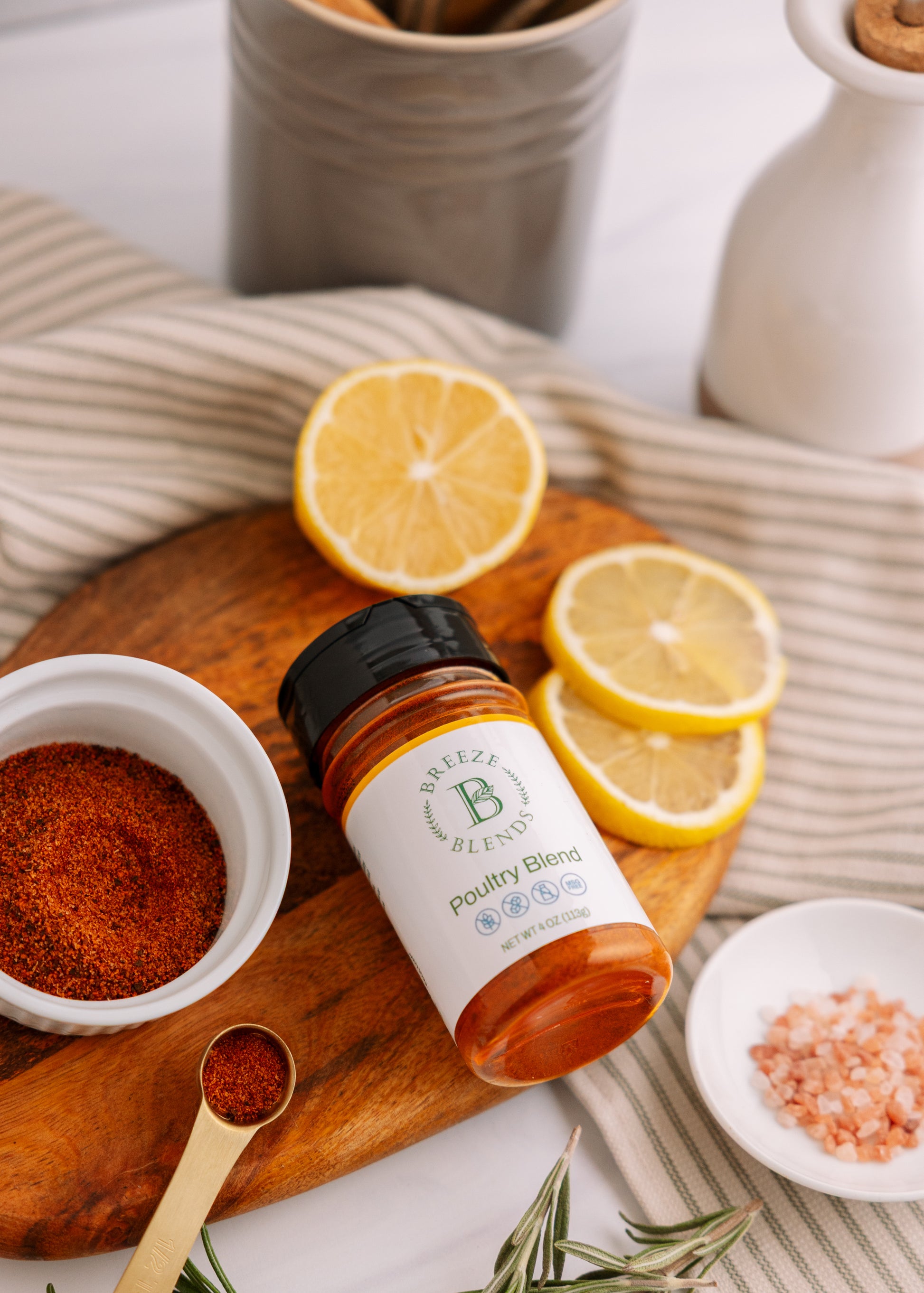 Bottle of Poultry Blend on a wooden cutting board with lemons and spices