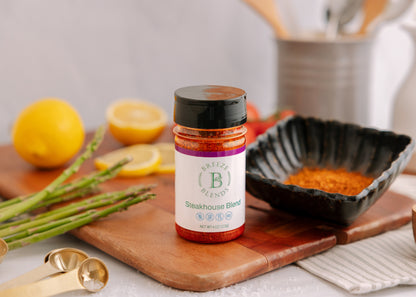 Bottle of steakhouse blend seasoning on a cutting board with lemons and asparagus.